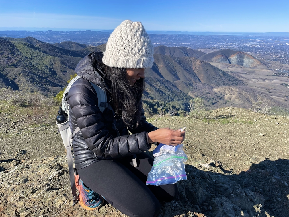 woman kneeling and signing peak book at Mount Olympia in Mount Diablo State Park