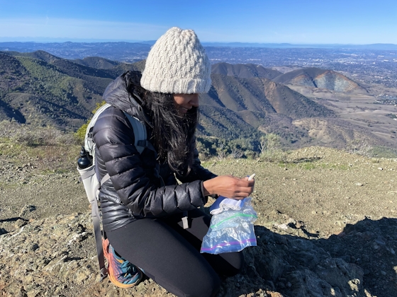 woman kneeling and signing peak book at Mount Olympia in Mount Diablo State Park