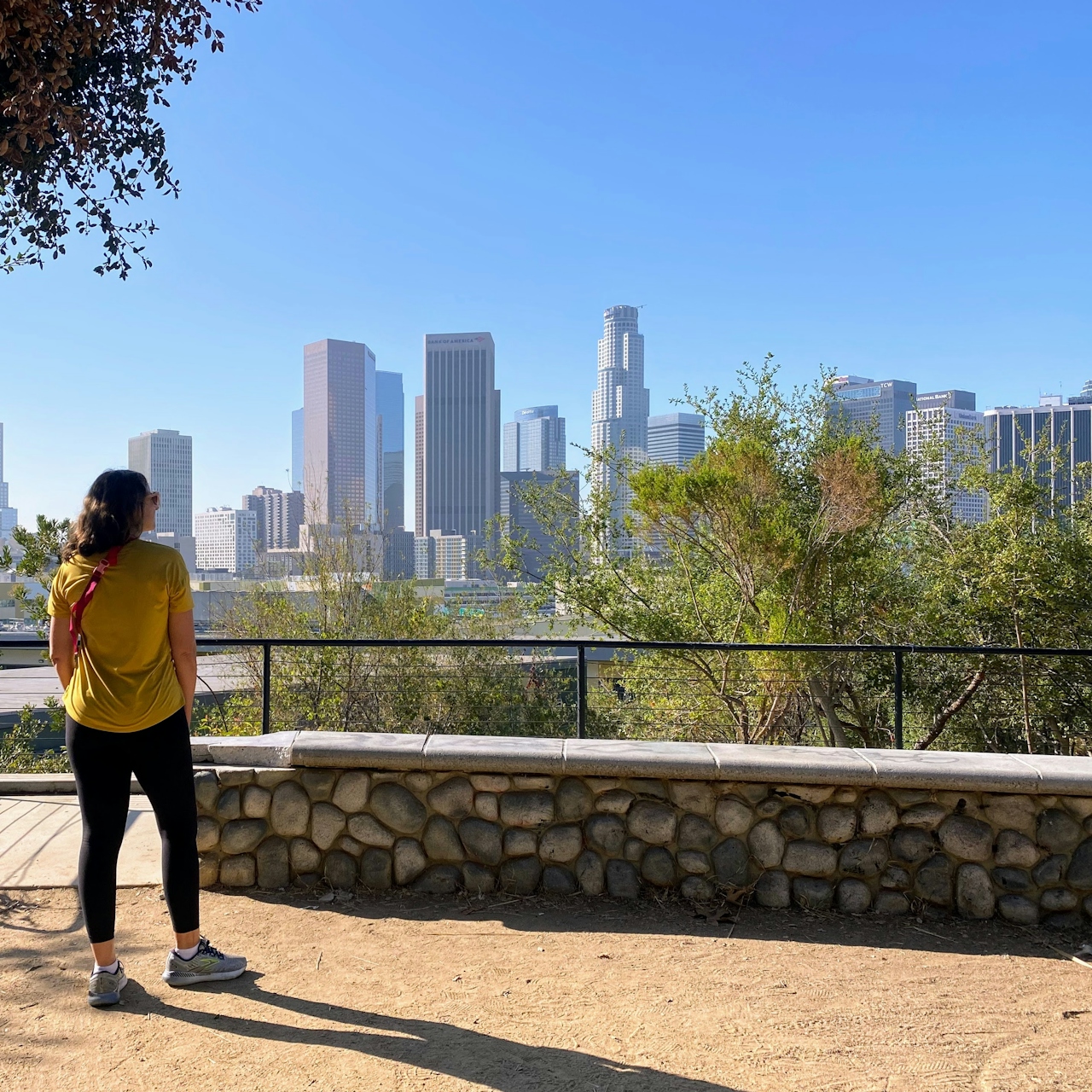 Woman standing at Vista Hermosa Park Overlook, looking out to the Los Angeles downtown skyline