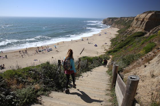 Woman Walking down stairs to a beach called Cowell Ranch State Beach 