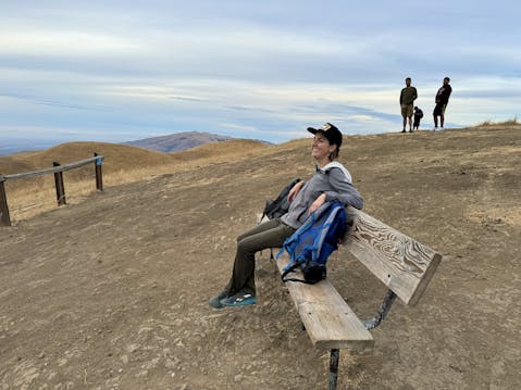 Woman sitting on a bench overlooking scenery at Sierra Vista Open Space Preserve