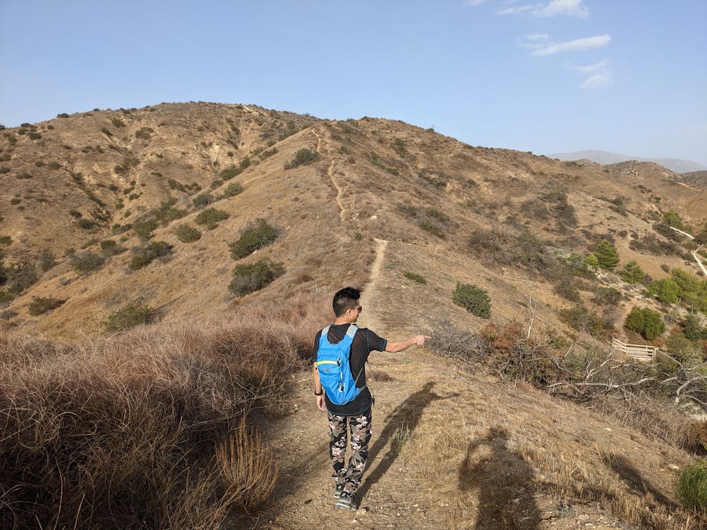 Hiker pointing to something with his long shadow reflected on the hiking trail at Shadow Hills in Burbank 