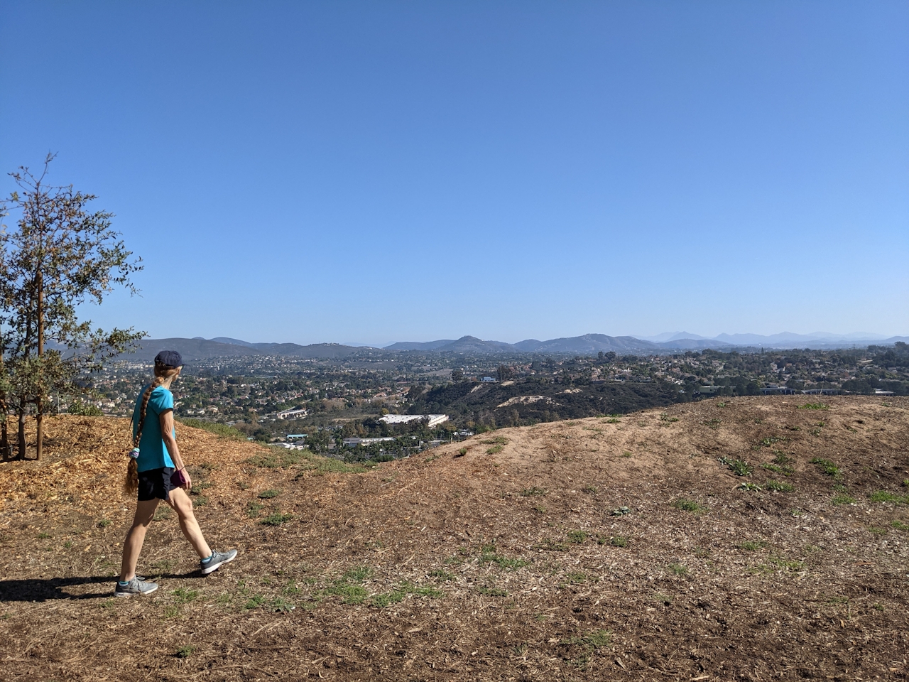 Hiker walks along a trail and looks out to the mountain scenery at Enicinitas Ranch in North San Diego County 