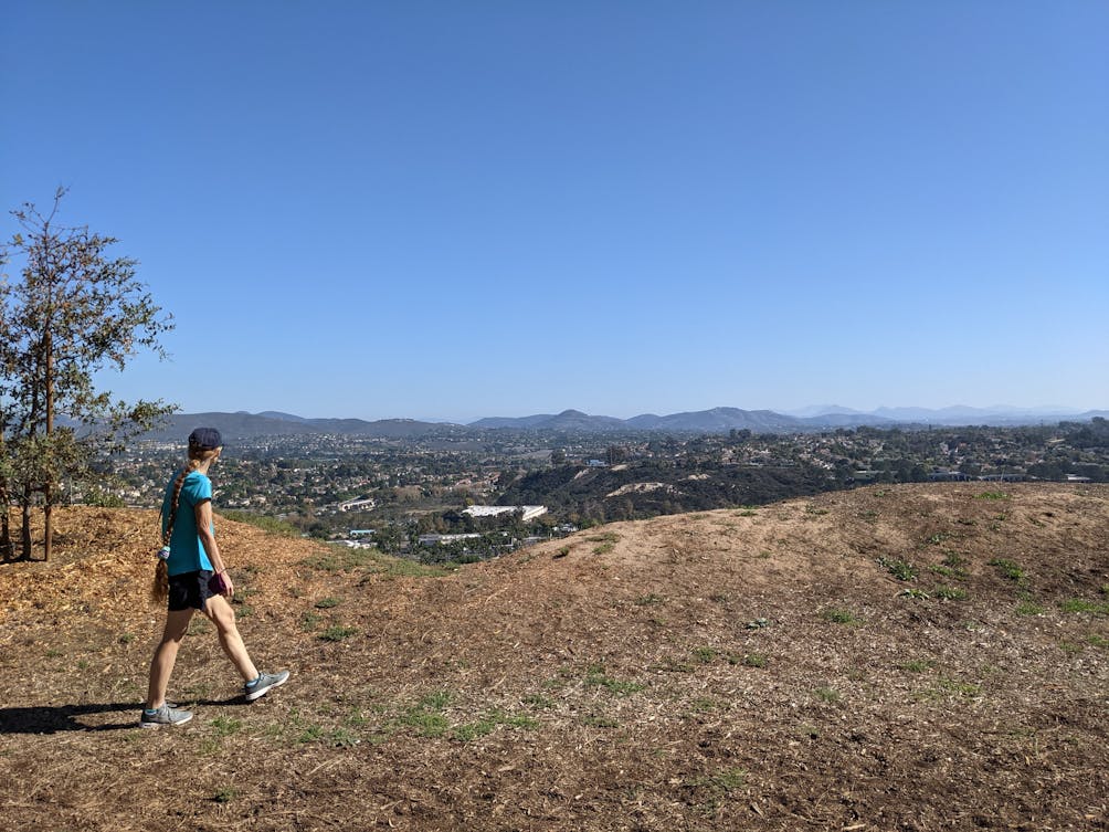Hiker walks along a trail and looks out to the mountain scenery at Enicinitas Ranch in North San Diego County 