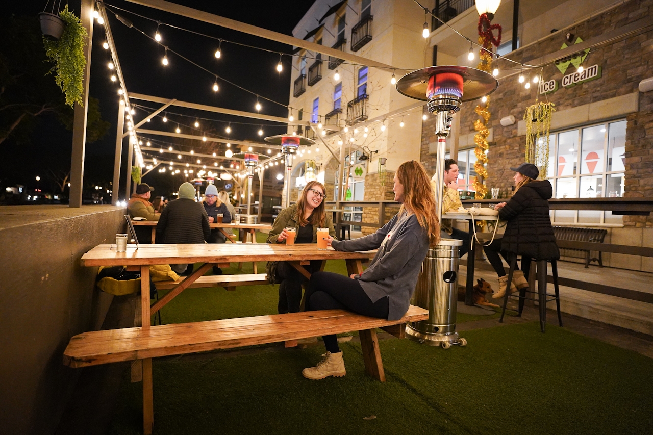 Beer drinkers on Topa Topa Camarillo outdoor patio with string lights and heat lamp and picnic tables 