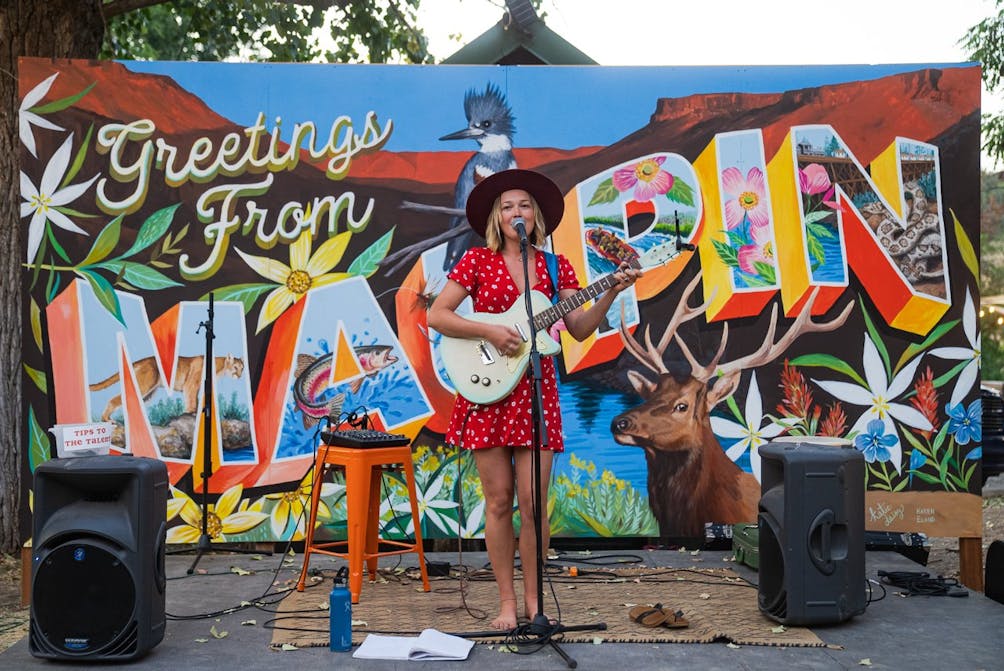 Woman singing in front of Oregon mural