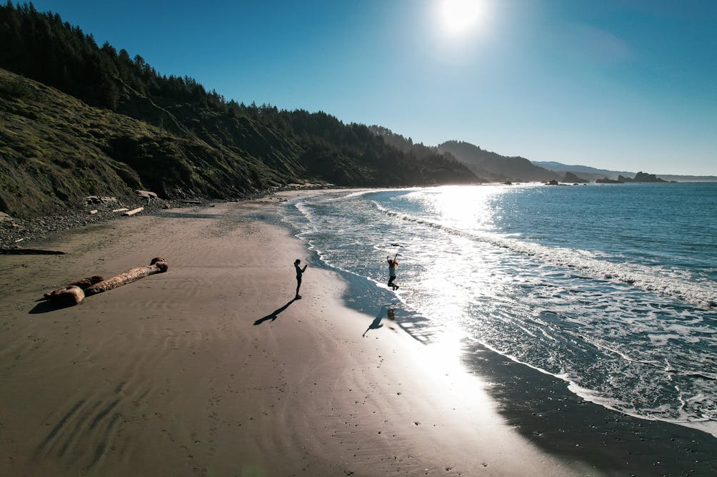 Hikers enjoying the wide open beach of Hunters Cove that you hike into on the Cape Sebastian Trail on the Oregon Coast