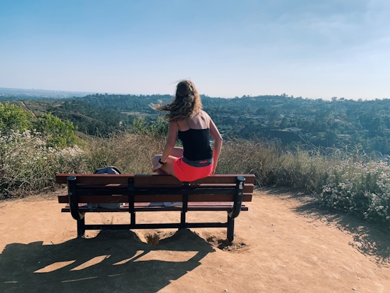 Woman sitting on bench at Peters Canyon overlooking canyon scenery in Orange County