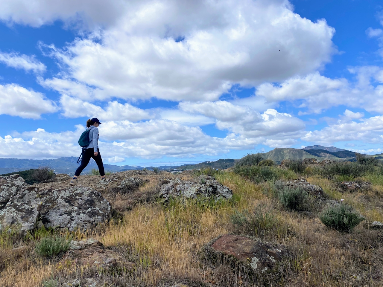 A woman walks across some large rocks and grassland at Wildwood Canyon in Thousand Oaks Ventura County 