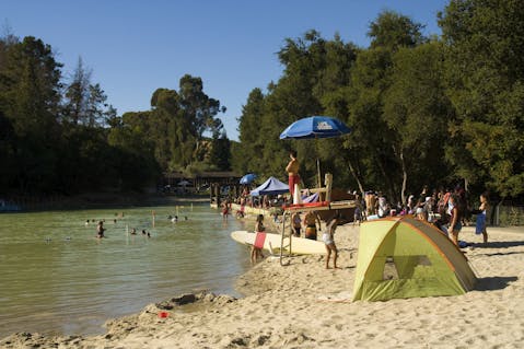 Surfboards and tents for shade are set up on the beach at Cull Canyon Regional Recreation Area in the Swim Lagoon Area 