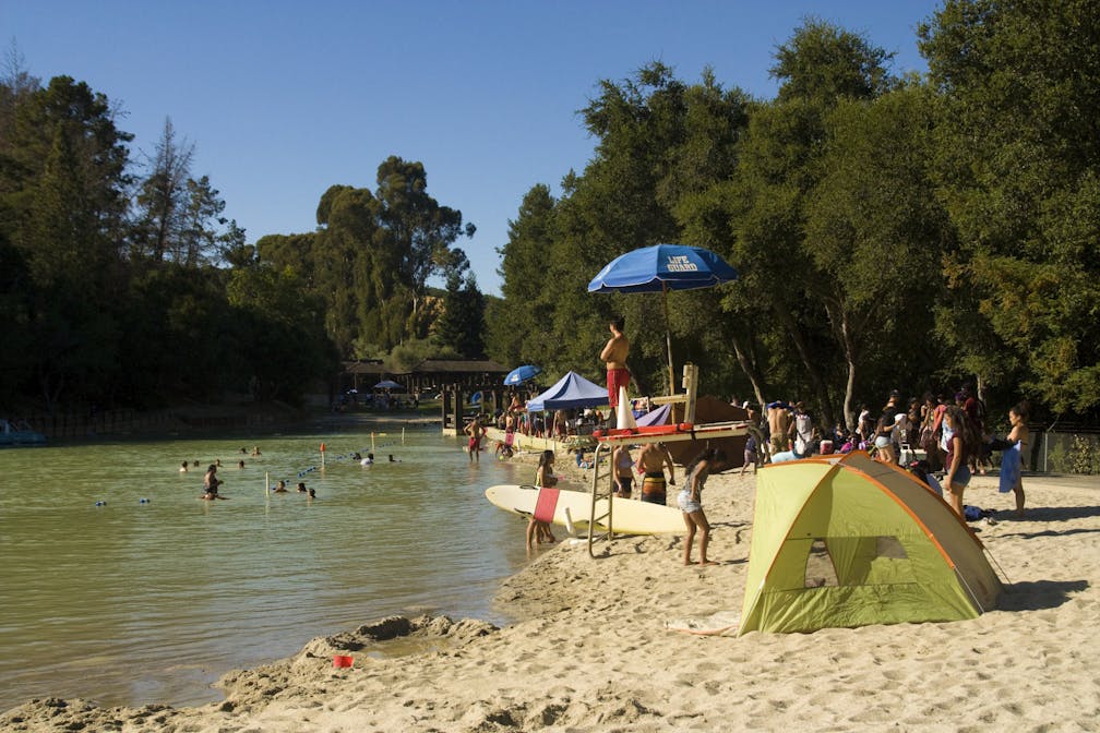 Surfboards and tents for shade are set up on the beach at Cull Canyon Regional Recreation Area in the Swim Lagoon Area 
