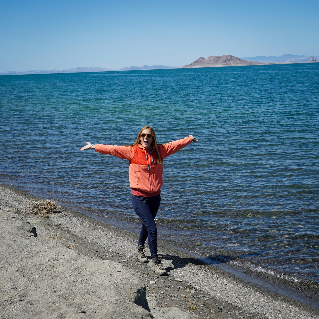 A woman walks happily along a beach shore at Pyramid Lake in Nevada 