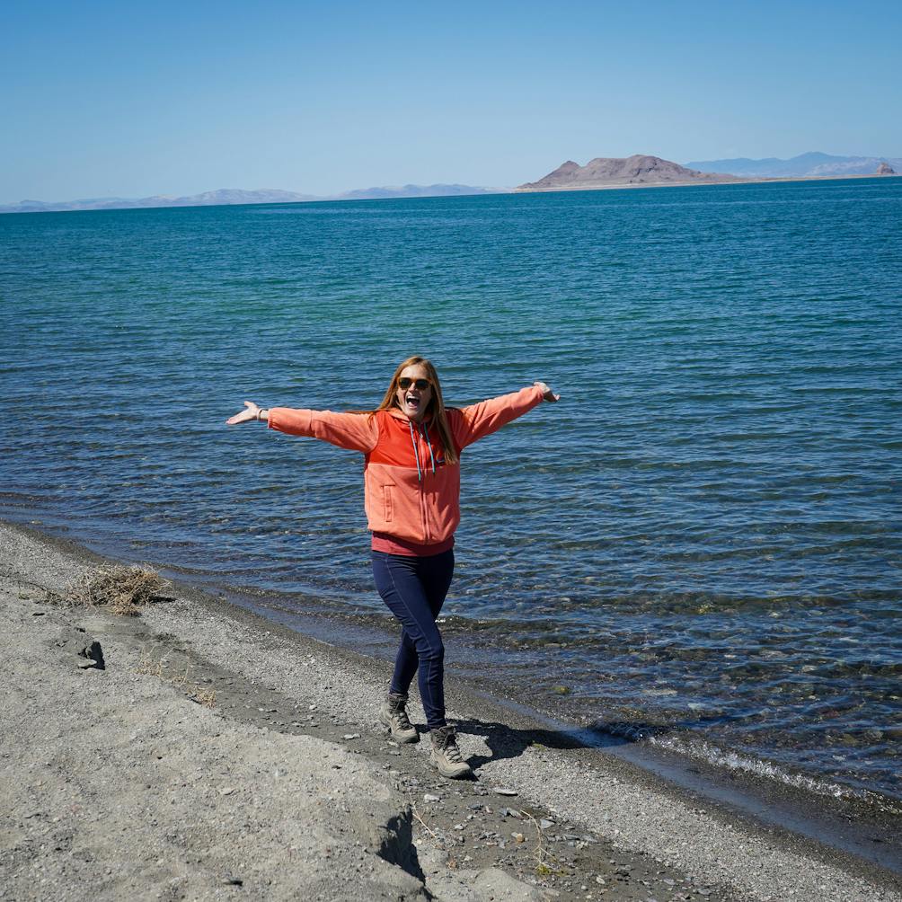 A woman walks happily along a beach shore at Pyramid Lake in Nevada 