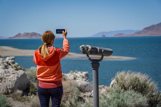 A woman takes a photo of Pyramid Lake with her phone 