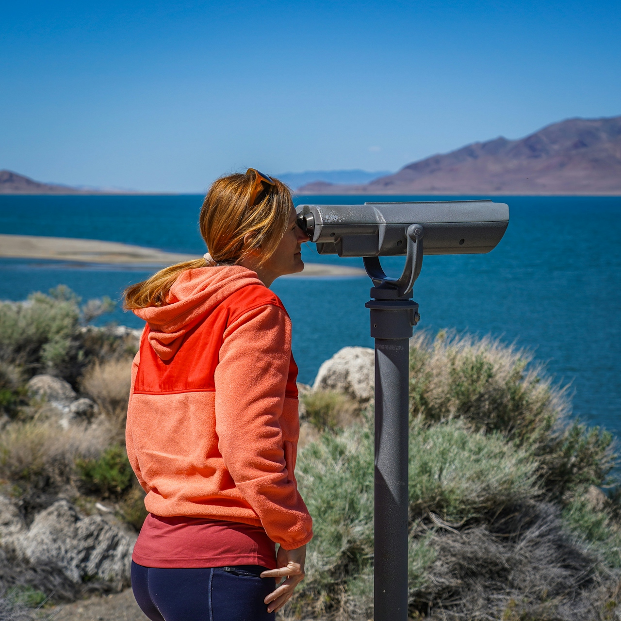 A woman looks through binoculars at Pyramid Lake 