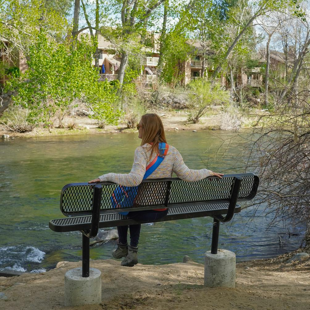 A woman sits on the bench overlooking the Truckee River at Oxbow Nature Study Area 