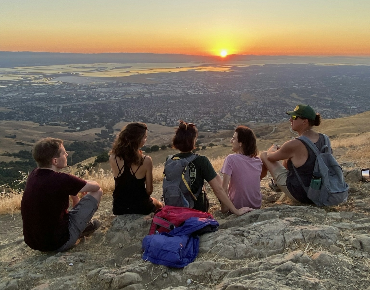 A group of friends sitting down and hanging out at the summit of Mission Peak in the Bay Area