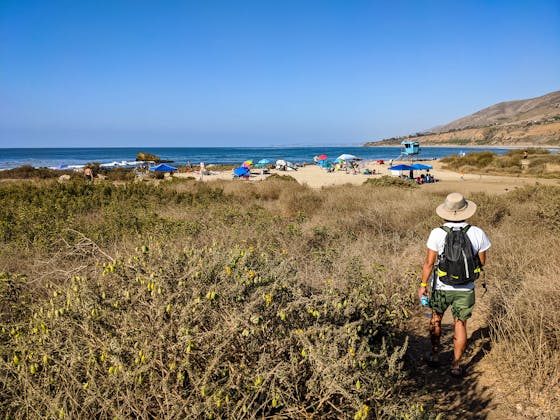 A hiker walks towards Leo Carrillo Beach via a hiking trail in Malibu