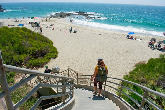 Woman hiker going down steps to Coast Royale Beach in Orange County, Southern California 