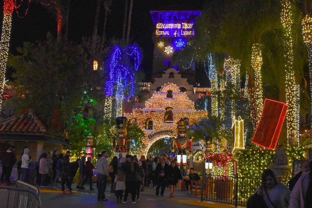Lots of people walking around the Mission Inn in Riverside California looking at all the red and white and purple holiday lights.