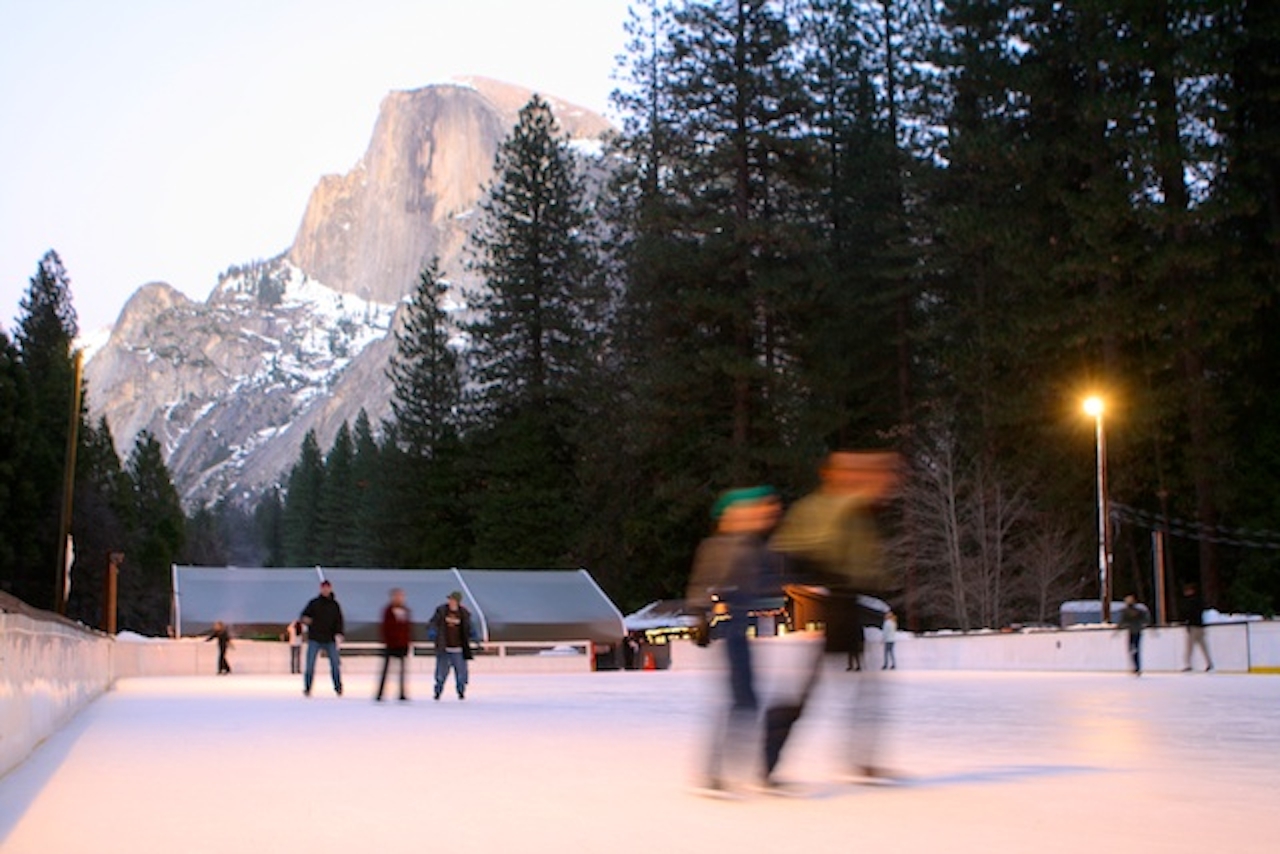 Ice skaters make their way around Curry Village Ice Rink with Half Dome in the background. 