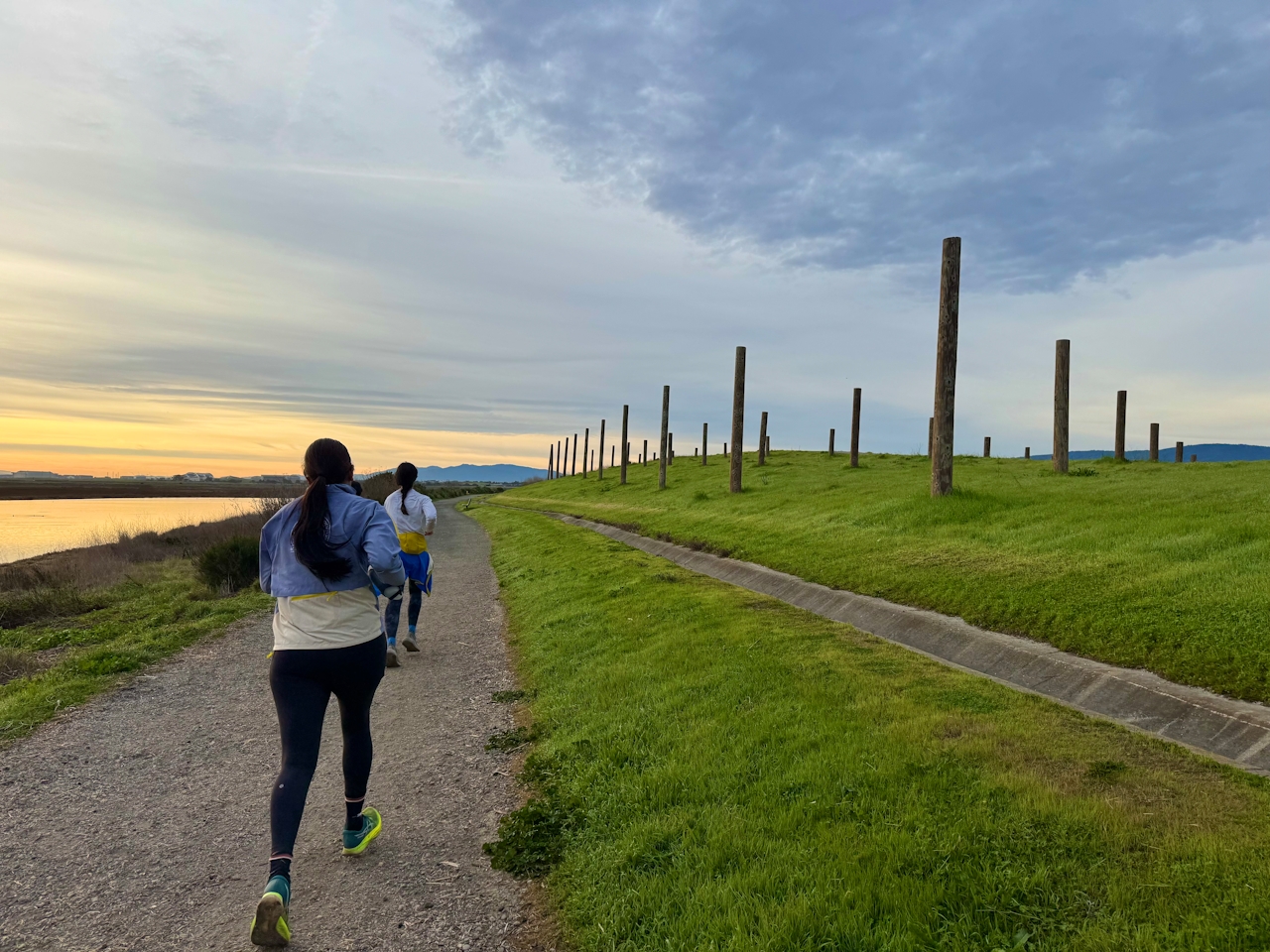 A woman fast walking a path next to an art installation called Pole Field at Baylands Nature Preserve in Palo Alto 