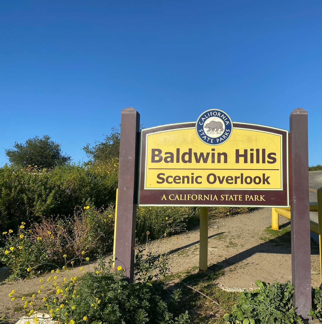 A large and yellow based entry sign for Baldwin Hills Scenic overlook