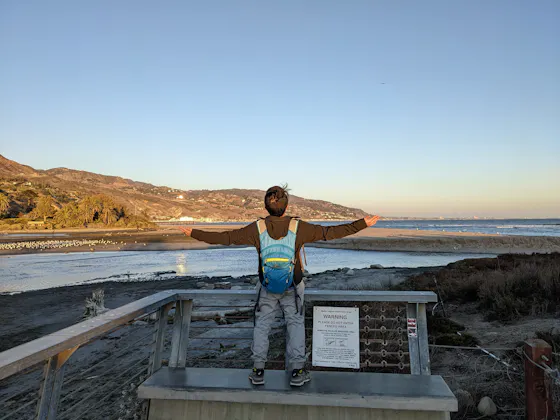 A young man opens his arms out in appreciation of the beautiful scenery of Malibu Lagoon