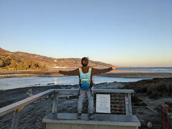 A young man opens his arms out in appreciation of the beautiful scenery of Malibu Lagoon