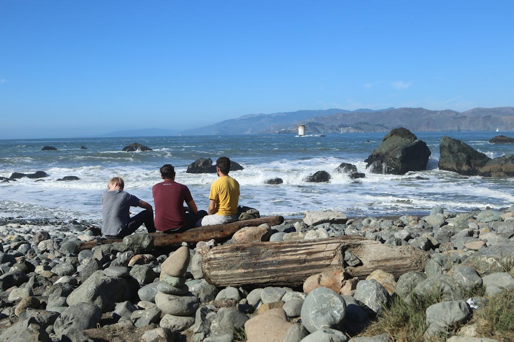 Hikers sitting at Mile Rock Beach in San Francisco 