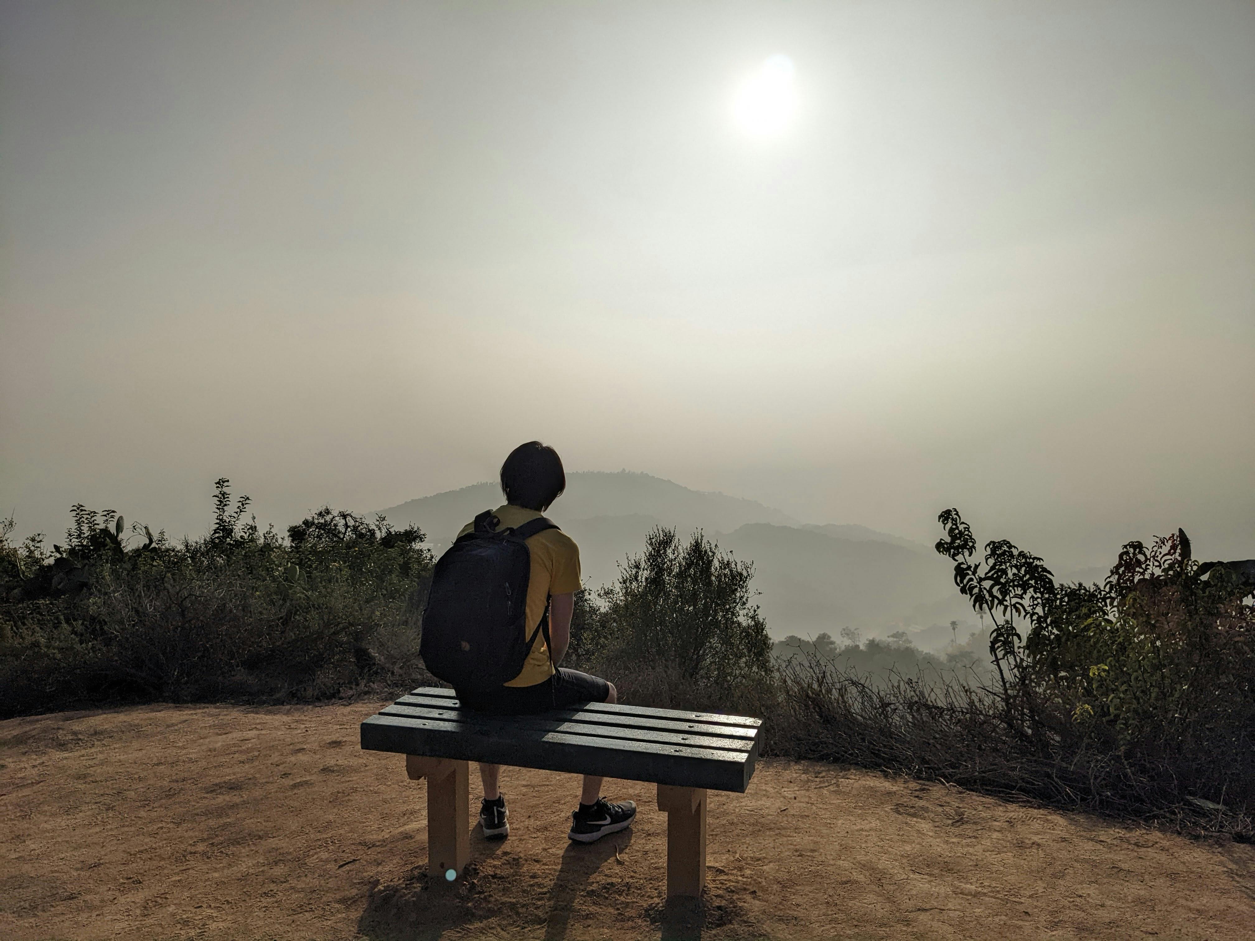 HIker sitting on a bench overlooking mountains at Hillside Wilderness Preserve in Monrovia 