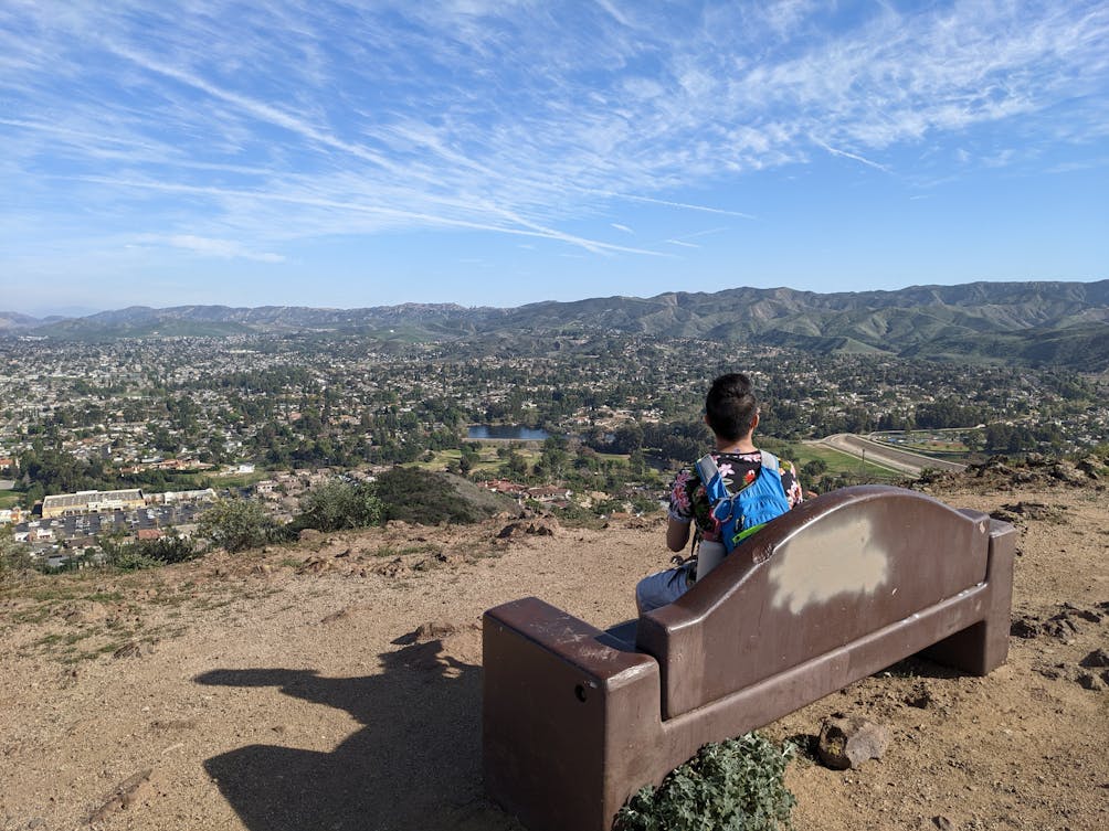 Hiker sitting at a bench on Mount McCoy near a giant cross overlooking Simi Valley 