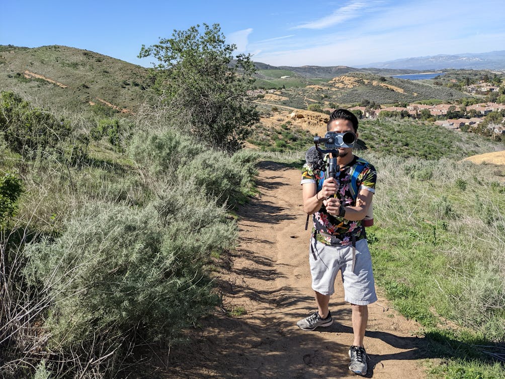 Hiker with a video camera pointing toward the photo camera at Long Canyon in Simi Valley 