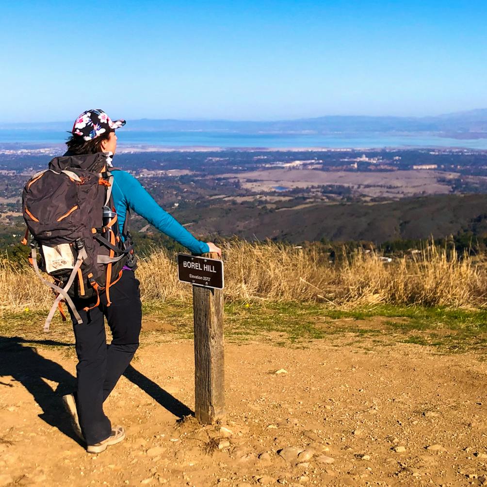 Hiker at the sign for Borel Hill at Russian Ridge Open Space Preserve 
