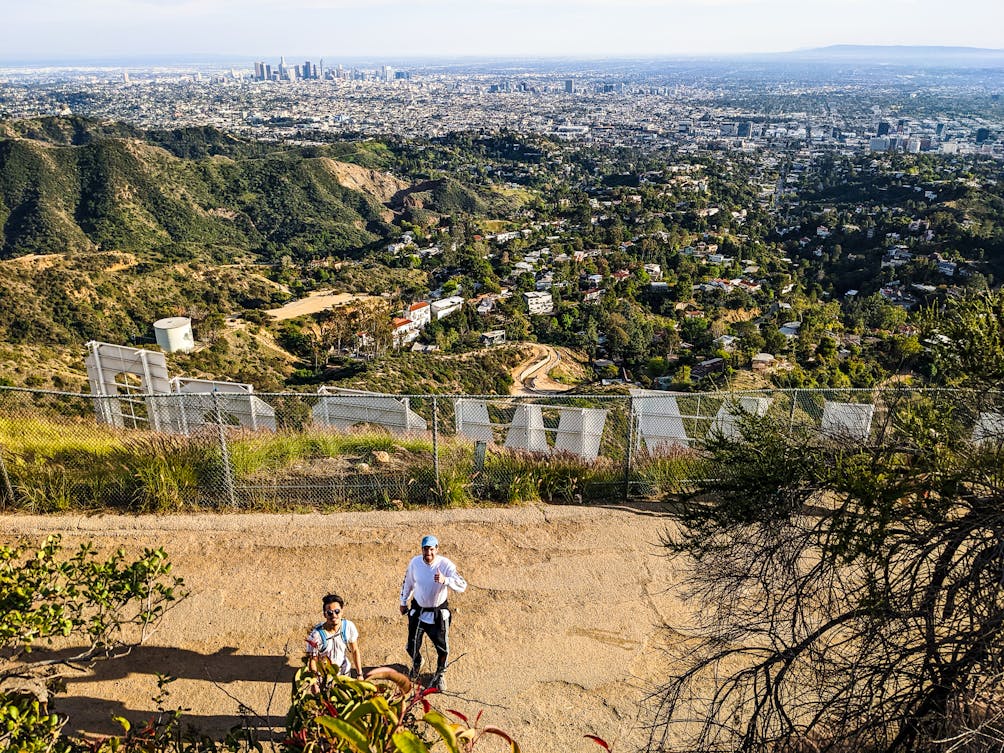 Hikers behind the Hollywood Sign overlooking Los Angeles on a hiking trail in Griffith Park 