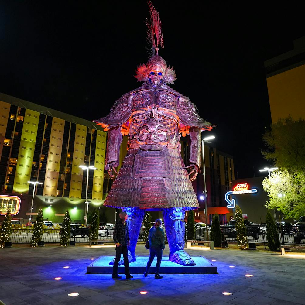 couple looking at giant samurai burning man art on neon line Reno