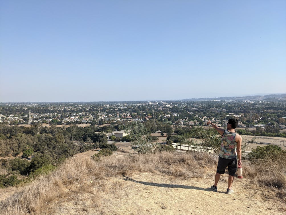 Hiker pointing out to valley views on a hiking trail at Horsethief Canyon Park in San Dimas