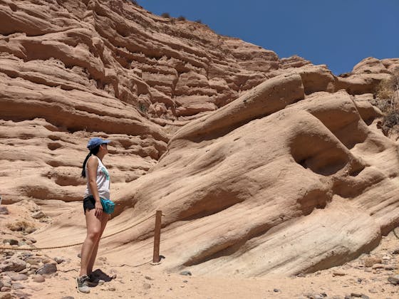 Woman standing and observing the red rock formation at the end of a hiking trail in Whiting Ranch Wilderness Park in Orange County 