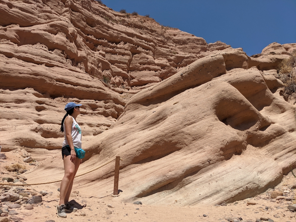 Woman standing and observing the red rock formation at the end of a hiking trail in Whiting Ranch Wilderness Park in Orange County