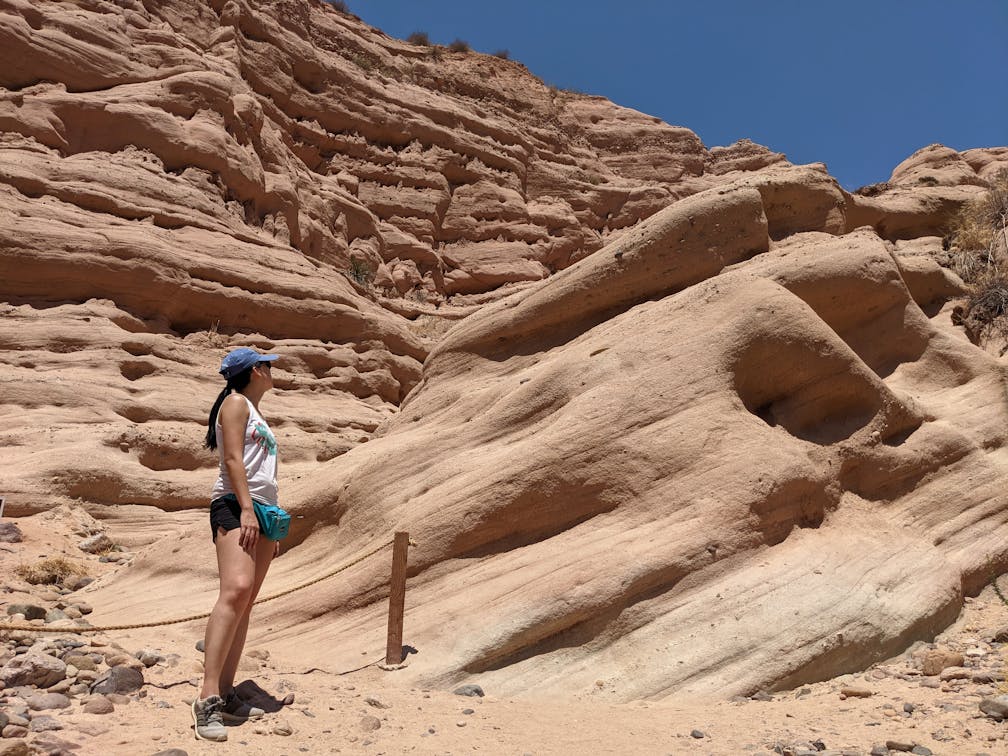 Woman standing and observing the red rock formation at the end of a hiking trail in Whiting Ranch Wilderness Park in Orange County 