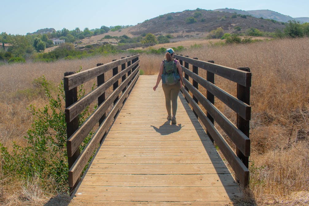 Hiker crossing over a bridge on the trail at Bommer Canyon Open Space Preserve in Orange County 