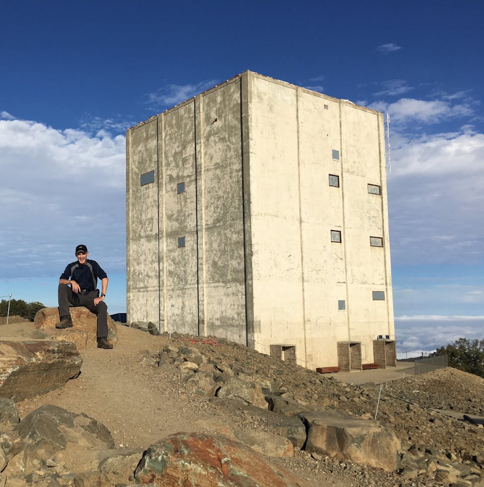 A person sitting in front of The Cube radar tower 