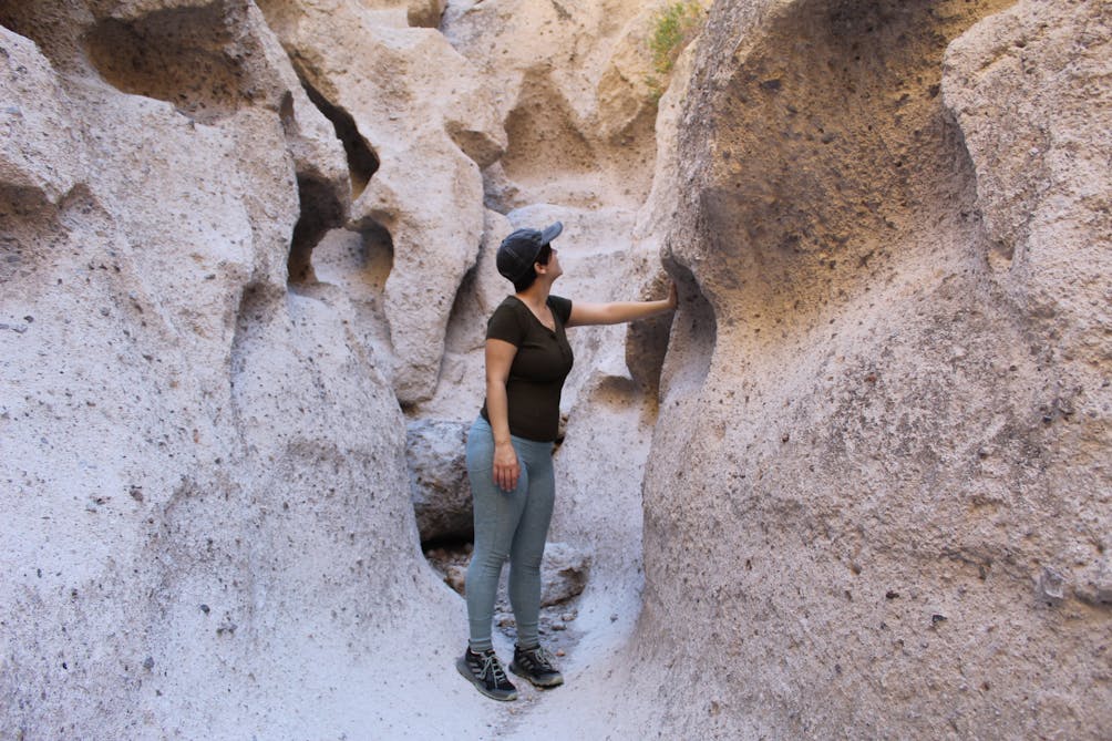 Hiker in a canyon feeling the sandstone formation at hole in the wall rings trail at Mojave Desert 