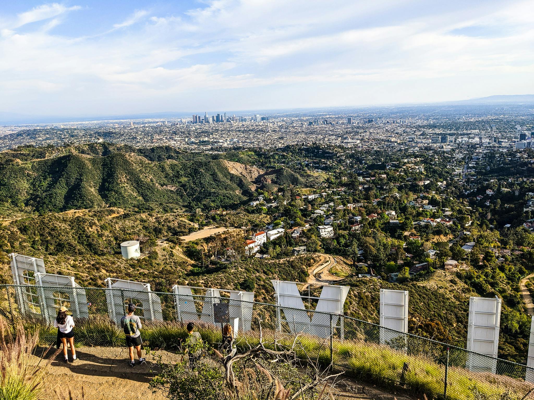 Hikers standing behind the Hollywood Sign letters overlooking Los Angeles 