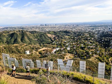 Hikers standing behind the Hollywood Sign letters overlooking Los Angeles 