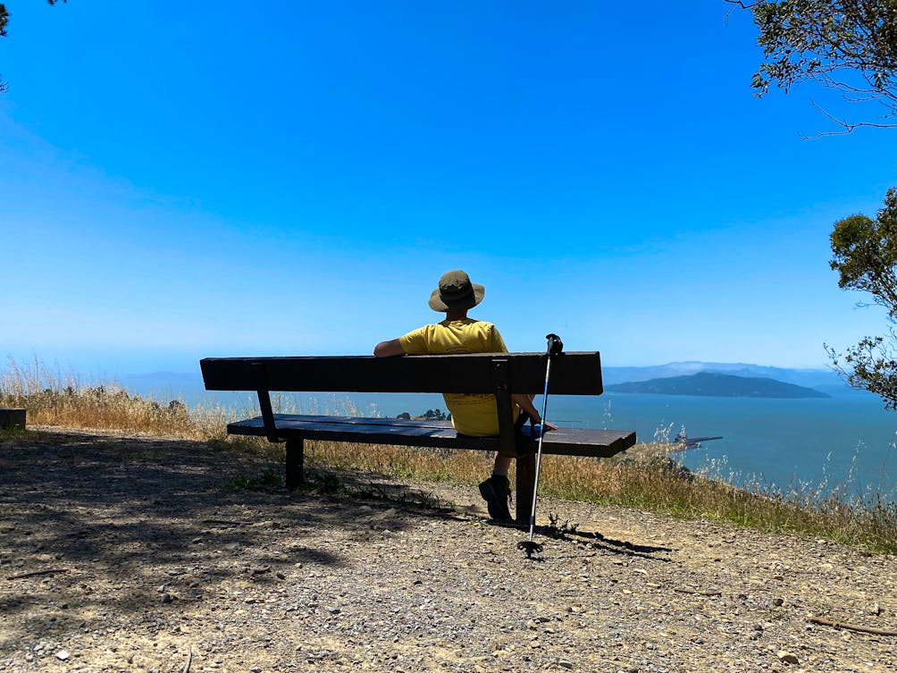 Person sitting at a bench overlooking the Golden Gate and Angel Island from Miller Knox Regional Shoreline East Bay 