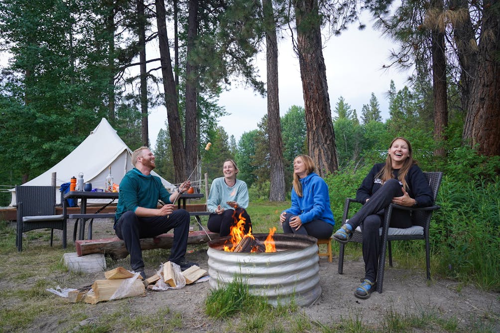 A group of friends around a campfire next to Fort Creek at Crater Lake Resort in Southern Oregon 
