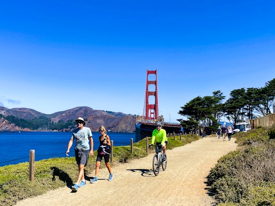 Bikers and walkers on the Bay Area Ridge Trail with the Golden Gate Bridge behind them
