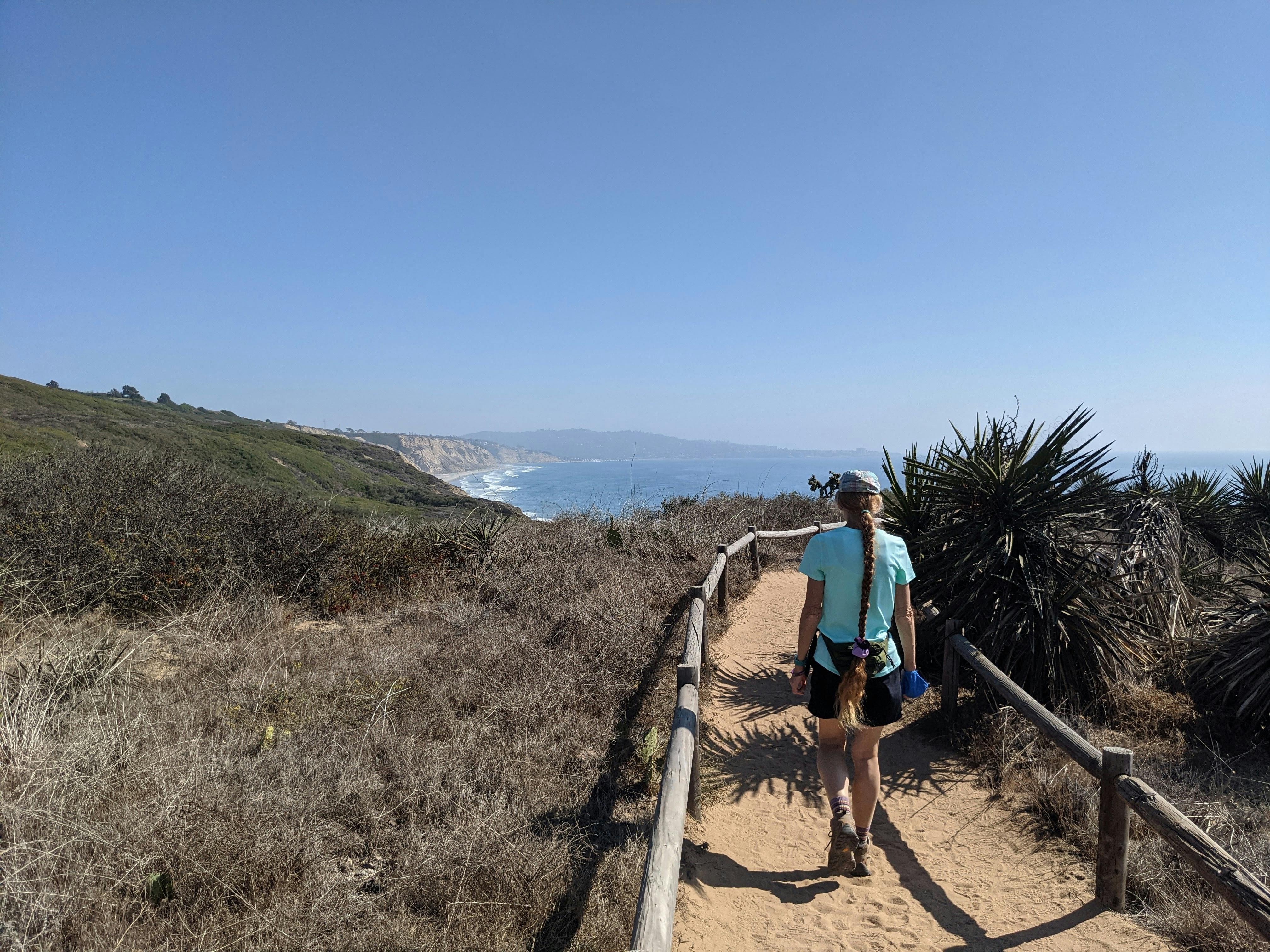 Woman hiking a trail overlooking the Pacific Ocean at Torrey Pines State Reserve in San Diego County 