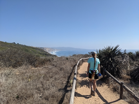 Hiker on a trail overlooking the Pacific ocean at Torrey Pines State Natural Reserve in San Diego County